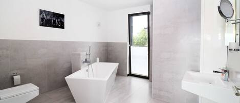Un baño moderno con una bañera grande, un lavabo blanco y un box de ducha de vidrio.