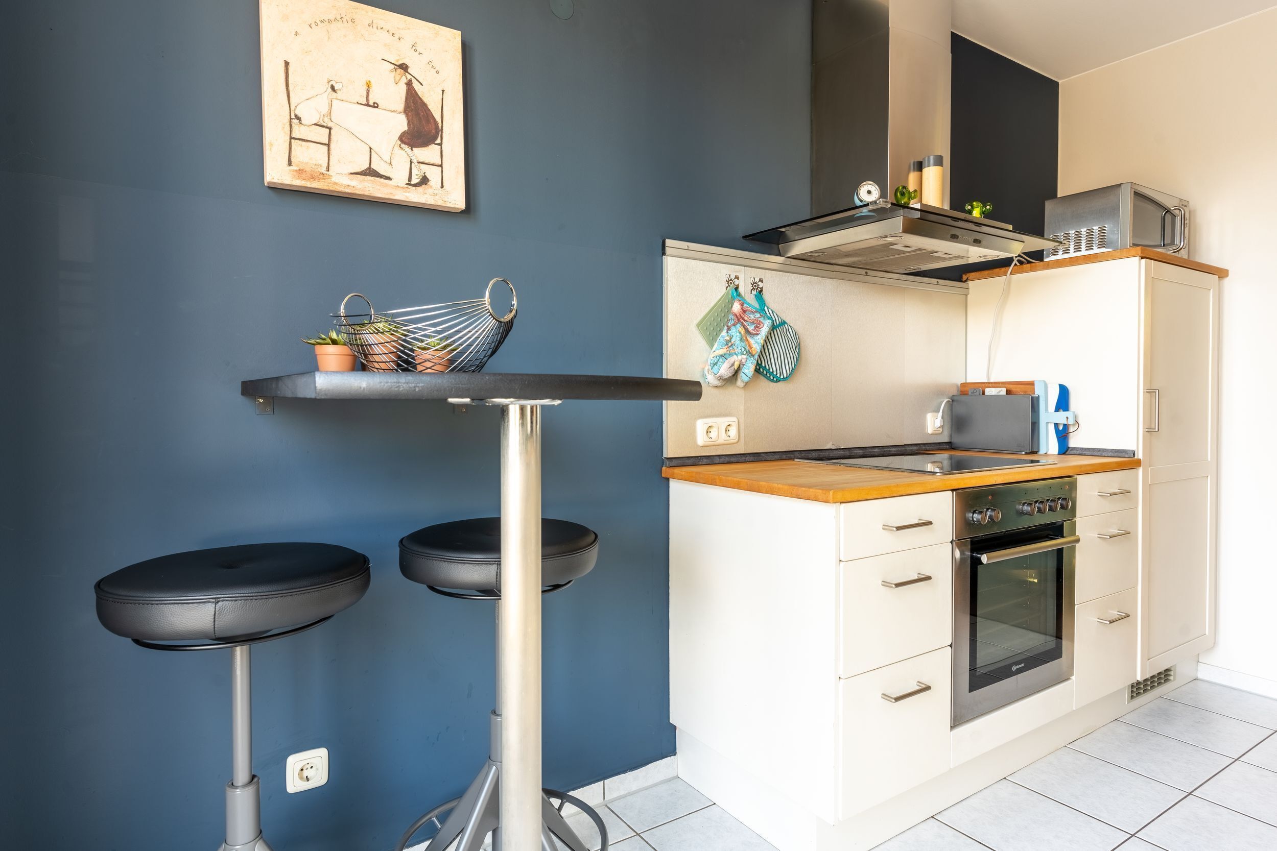 A compact kitchen with a bar stool, a microwave, and a stove.