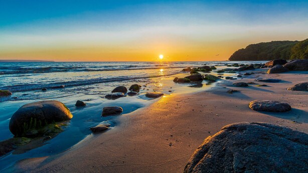 A beach with large rocks and a sunset over the ocean. - Ferienhaus Ivory, Deutschland (Binz)