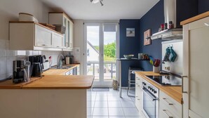 A modern kitchen with white cabinets, a wooden countertop, a built-in oven, and a view through the glass door to the outside. - Ferienhaus Ivory, Deutschland (Binz)
