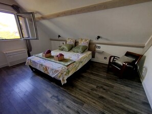 Un dormitorio con cama, una silla, un ventanal y un radiador.