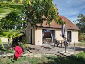 Una casa con patio, mobiliario exterior y jardín.