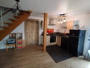 A kitchen with wooden cabinets, a black refrigerator, and a wooden staircase.