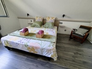 A bedroom with a bed, pillows, a chair, and a bedside table.