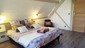 Een slaapkamer met een bed, kussens, een stoel en een houten deur.