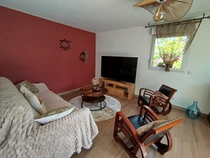 Una sala de estar con un sofá, sillas, un televisor y un ventanal con vistas.