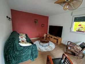 Una sala de estar con un sofá, una mesa de centro, un mueble para televisión y un sillón.