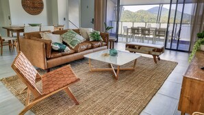 A modern living room with a leather sofa, a coffee table, and a dining area with a table and chairs. - Valle Vista Luxury Apartments (Redlynch)