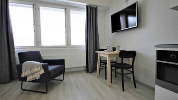 A modern room with a sofa, a small table, two chairs, a TV, and a built-in oven.
