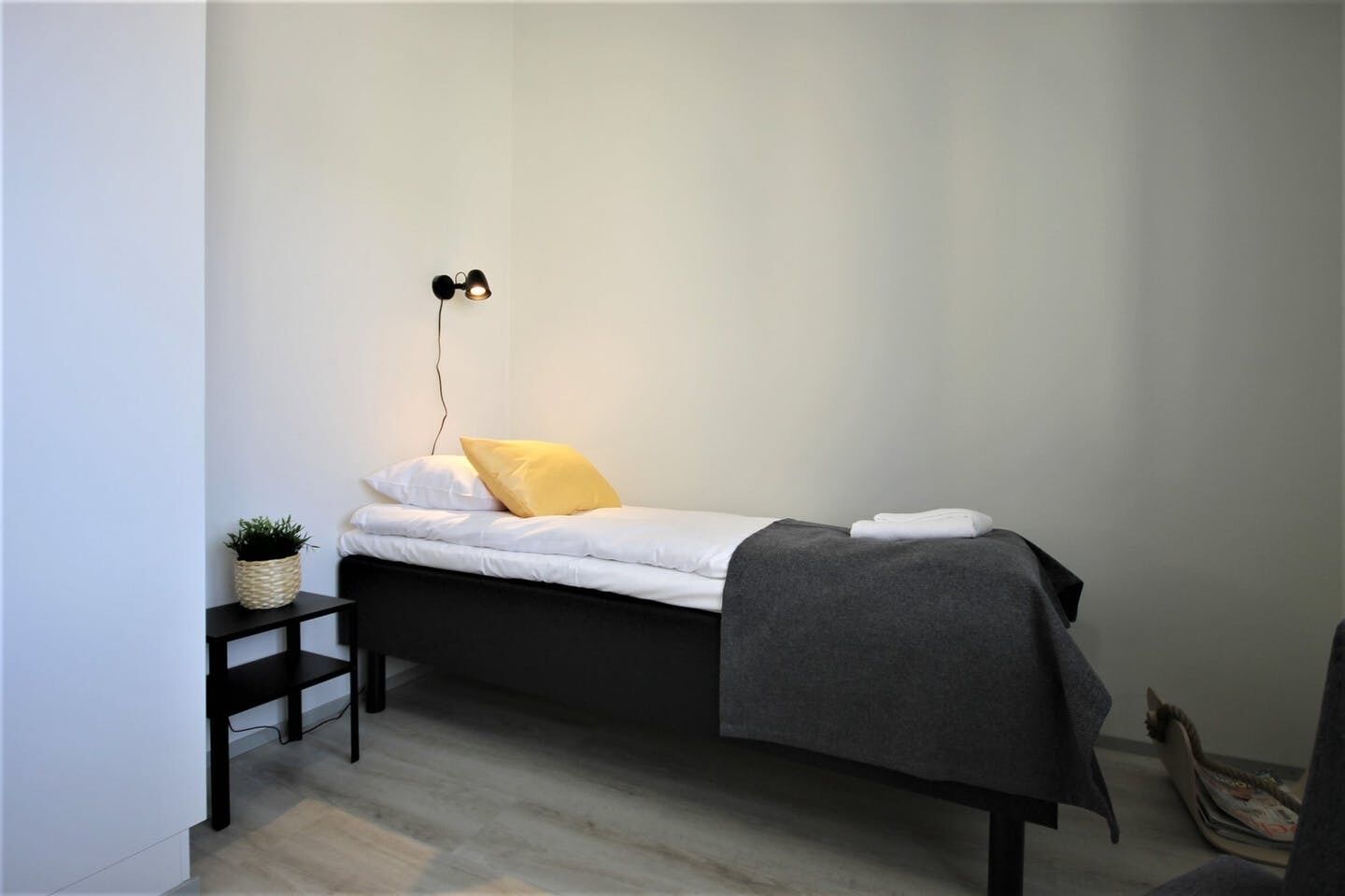 Un dormitorio minimalista con cama, mesita de noche y una lámpara de pared.