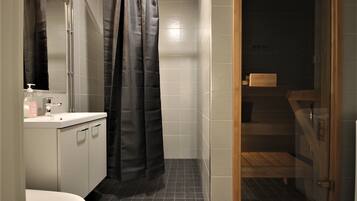A bathroom with a white sink, a mirror, a shower curtain, and a wooden bench.