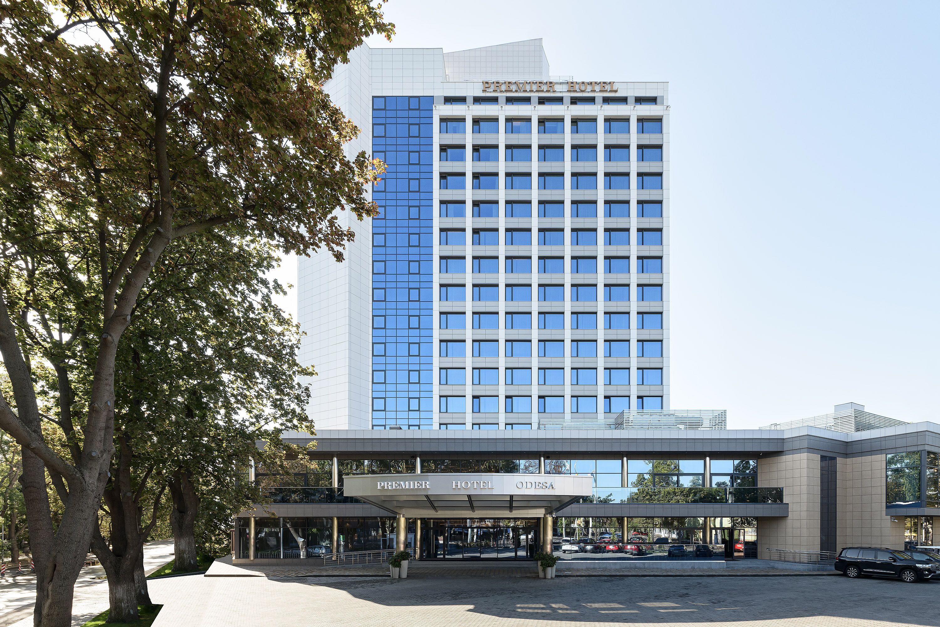 A modern hotel with a prominent glass facade and a covered entrance.