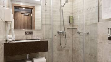 A modern bathroom with a glass-enclosed shower, a sink with a mirror above it, and a toilet.