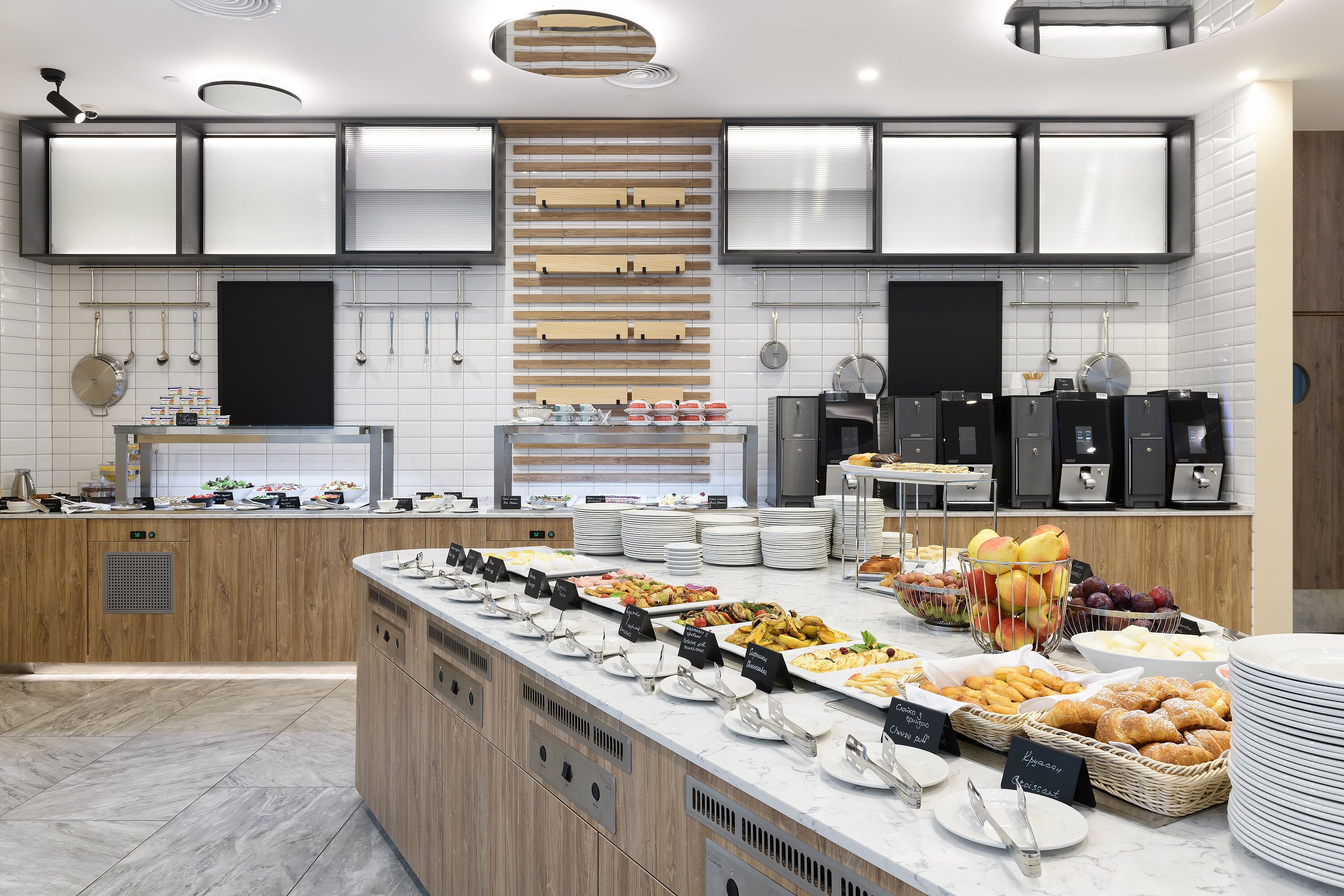 A modern kitchen with a central island, built-in appliances, and a variety of food items displayed on the counter.