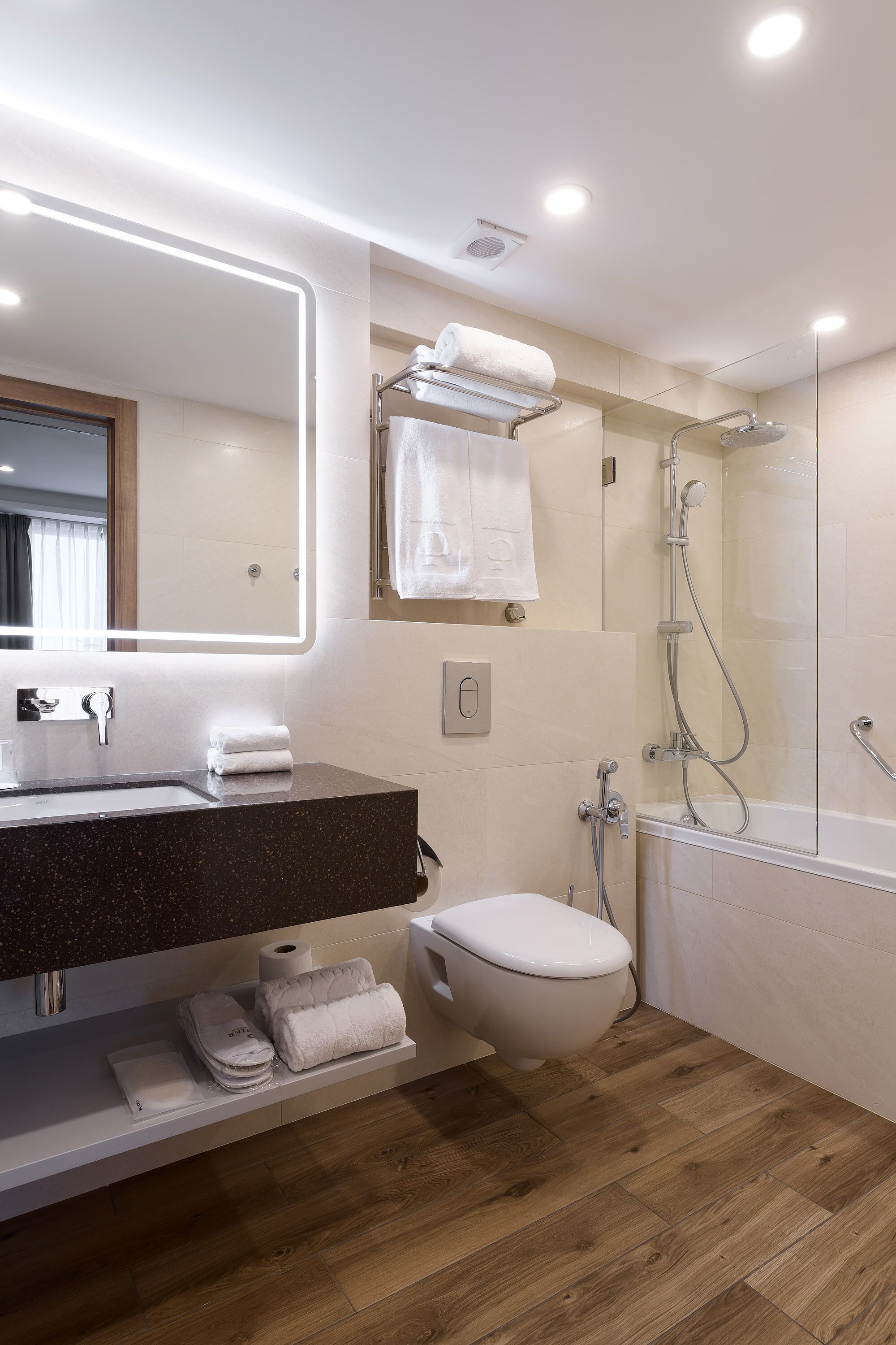 A modern bathroom with a dark granite sink, white tiles, a glass shower enclosure, and a wooden floor.