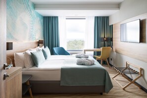 Een hotelkamer met een bed, een bureau, een stoel, een televisie en uitzicht op de omgeving.