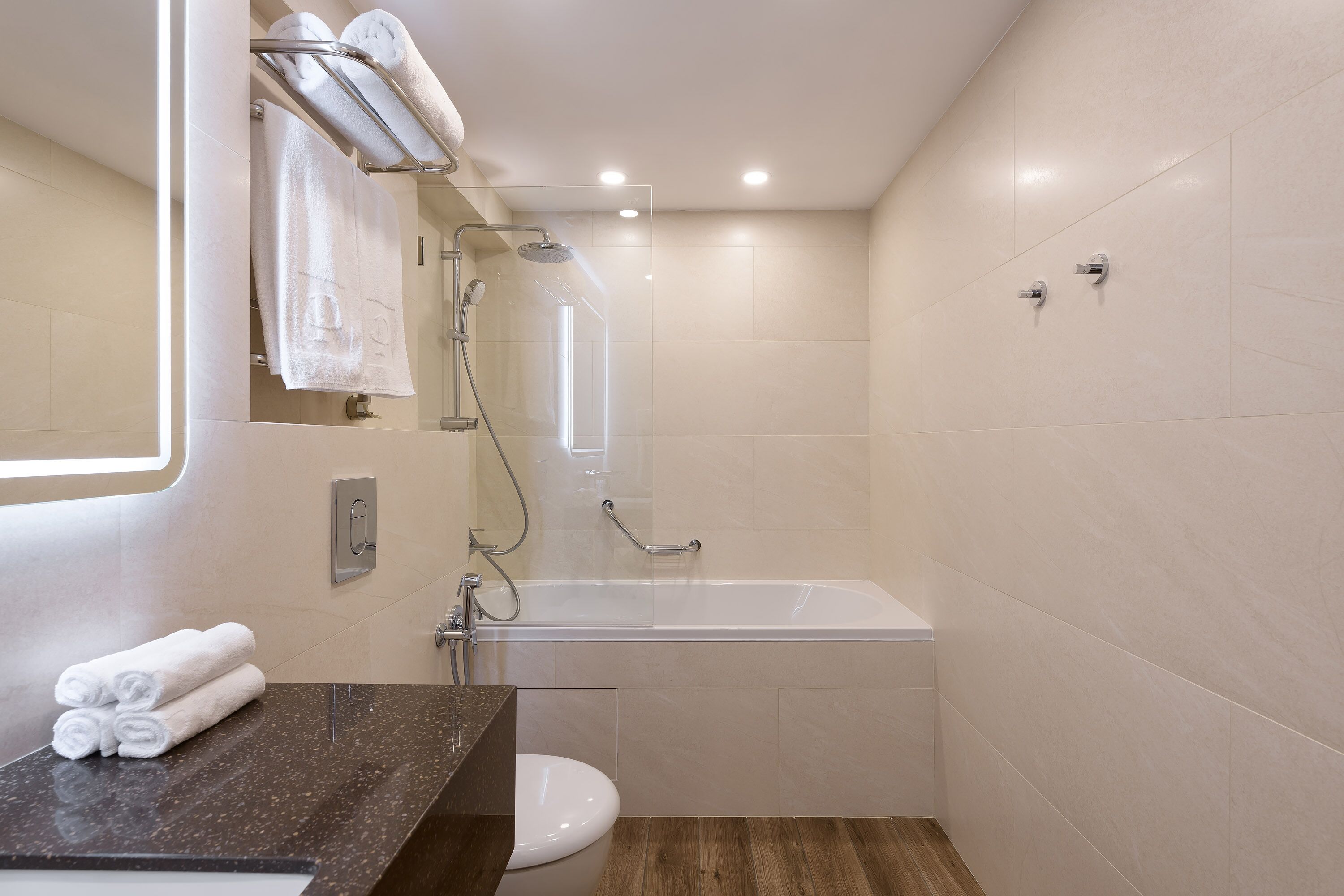 A modern bathroom with a bathtub, toilet, and a vanity with towels.