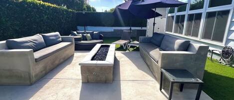 An outdoor patio with a fire pit, two sofas, and a small table.