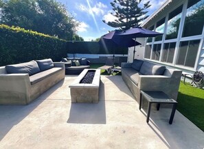 Une terrasse extérieure avec un foyer, deux canapés et une petite table.