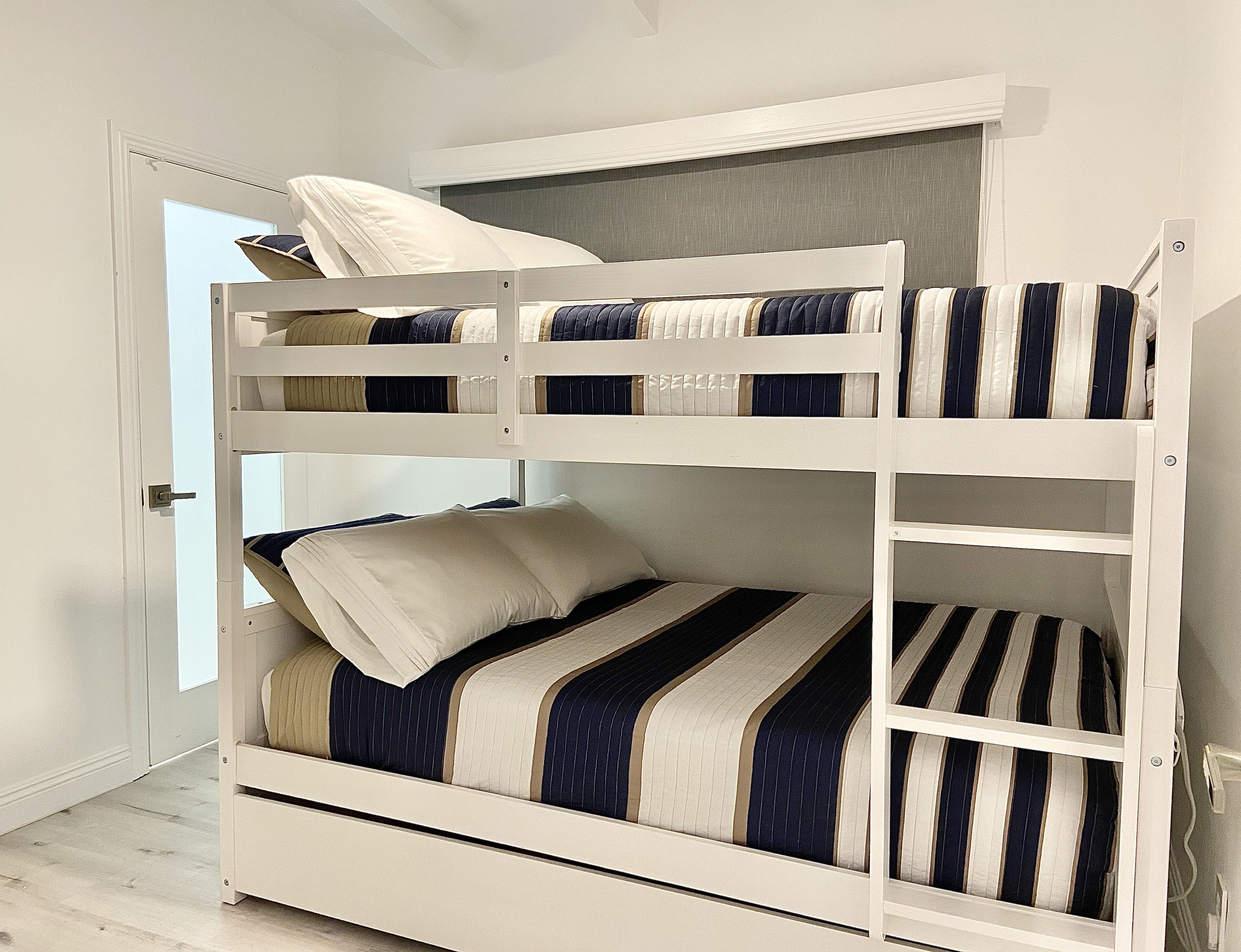 Un lit superposé à deux niveaux, chaque niveau étant équipé de son propre ensemble d’oreillers et de draps à rayures.