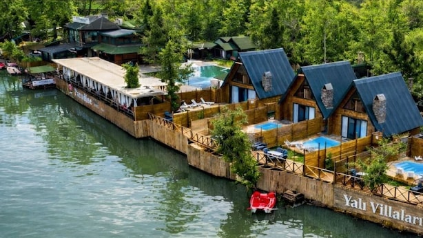 Un hotel flotante con varias cabañas, cada una con piscina y rodeado de agua.