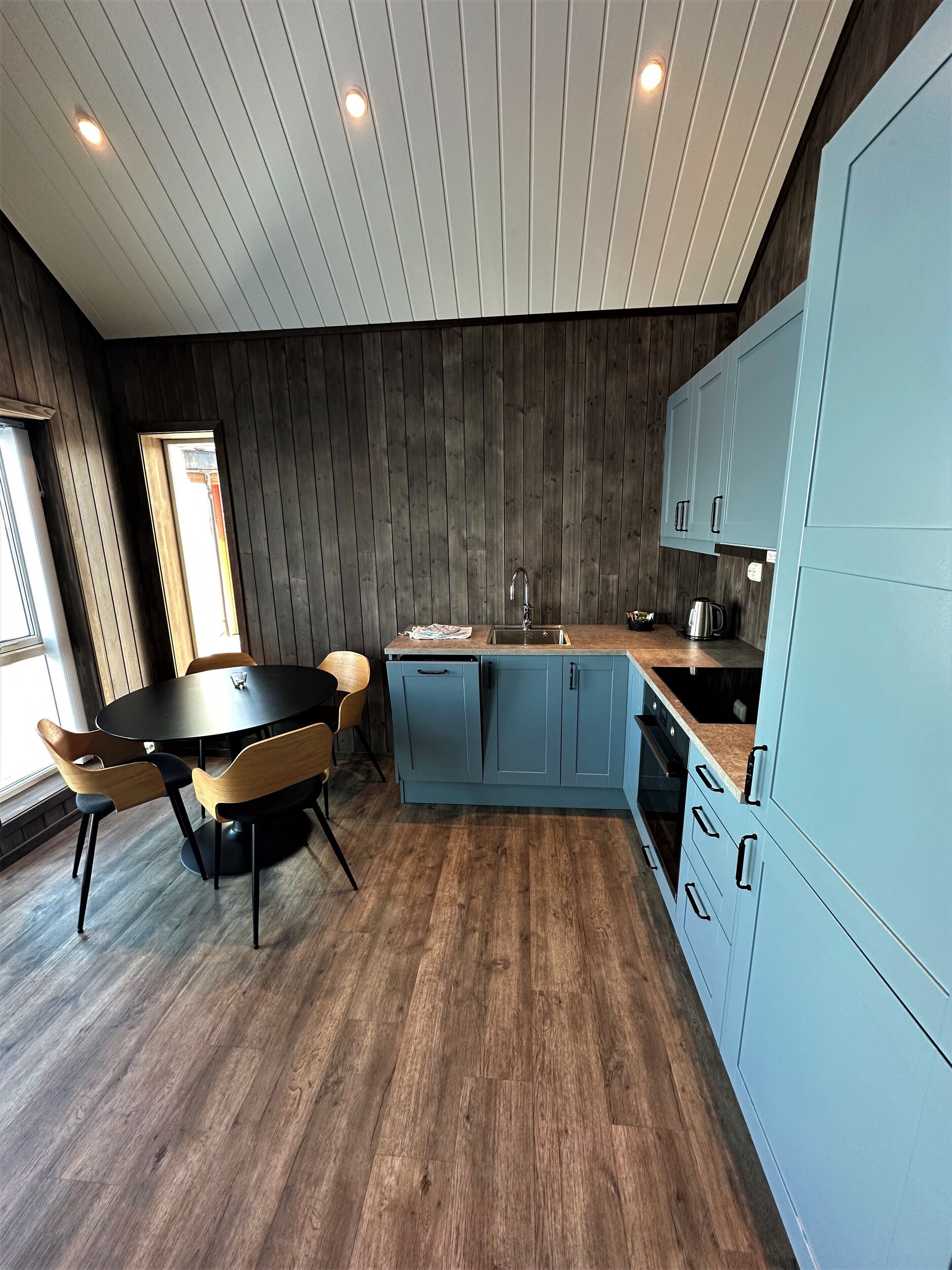 Una cocina moderna con suelo de madera, una mesa redonda para comer y armarios azul claro.