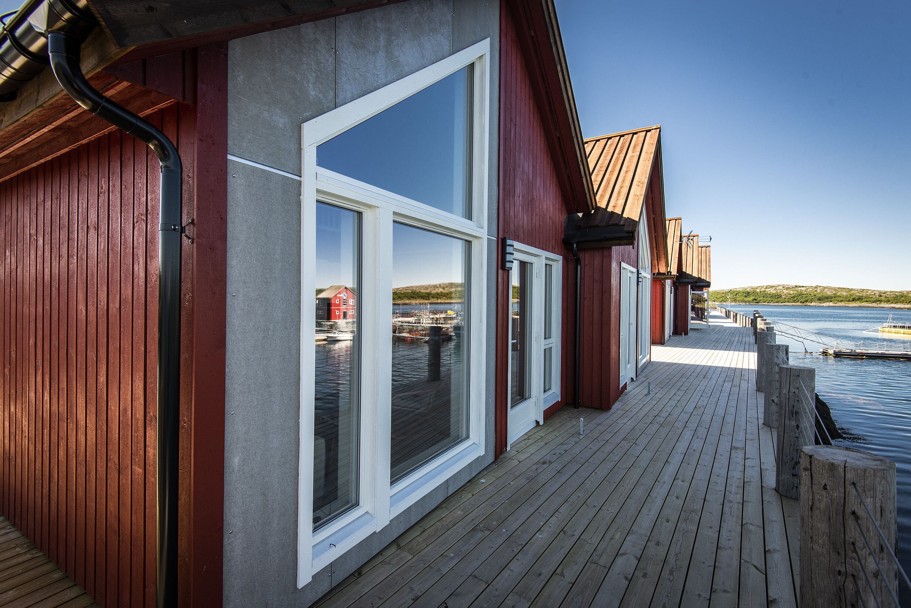 A wooden deck with large windows overlooking a body of water.
