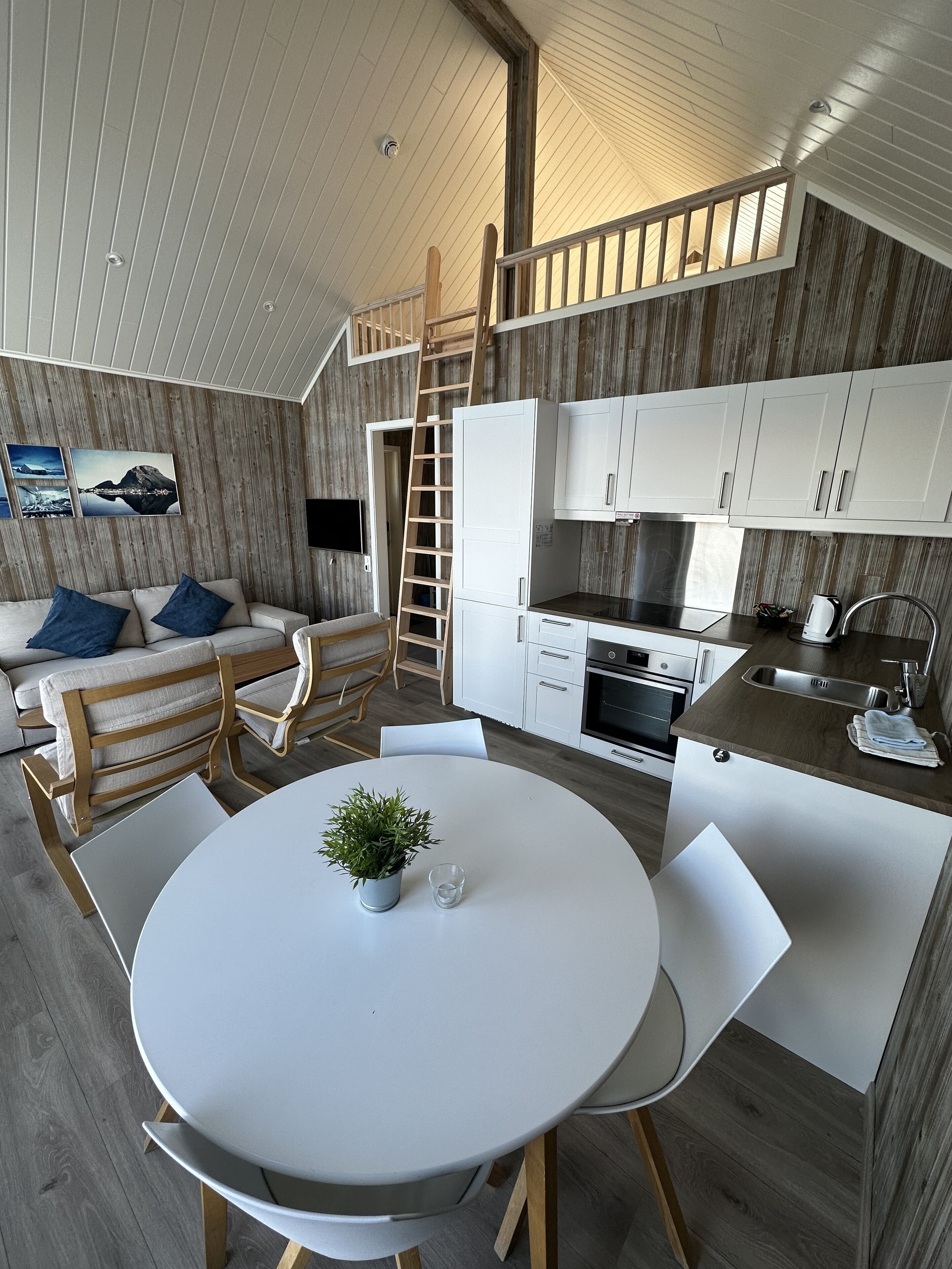 Una cocina moderna con armarios blancos, una estufa de acero inoxidable y una mesa de comedor de madera con sillas.
