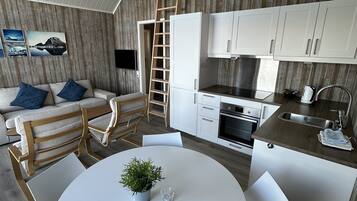 Una cocina moderna con armarios blancos, una estufa de acero inoxidable y una mesa de comedor de madera con sillas.