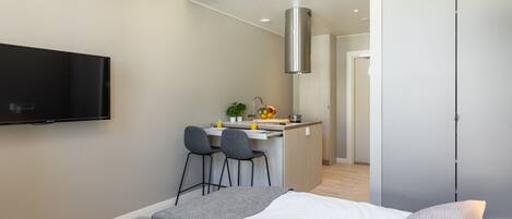 Una habitación de hotel moderna con cama, televisión, kitchenette y zona de comedor.