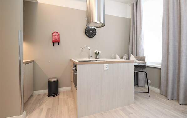 A modern kitchen with a central island, stainless steel sink, and a clock on the wall. - Forenom Aparthotel Vaasa (Vaasa)