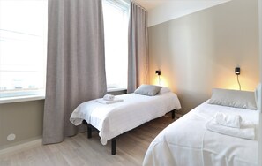 A hotel room with two beds, a window with curtains, and wall-mounted lights. - Forenom Aparthotel Vaasa (Vaasa)