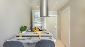 Une cuisine moderne avec un îlot central, deux chaises grises et un panier de fruits.