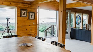 L’intérieur est en bois et comprend une table à manger, des chaises et un télescope. Des tableaux encadrés ornent les murs, et de grandes fenêtres offrent une vue sur l’extérieur.