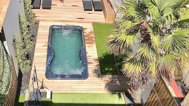 Um quintal com hidromassagem, deck de madeira e área de estar.
