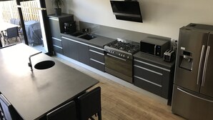 Cozinha moderna com fogão a gás, pia e eletrodomésticos em aço inoxidável, incluindo uma geladeira e uma torradeira.