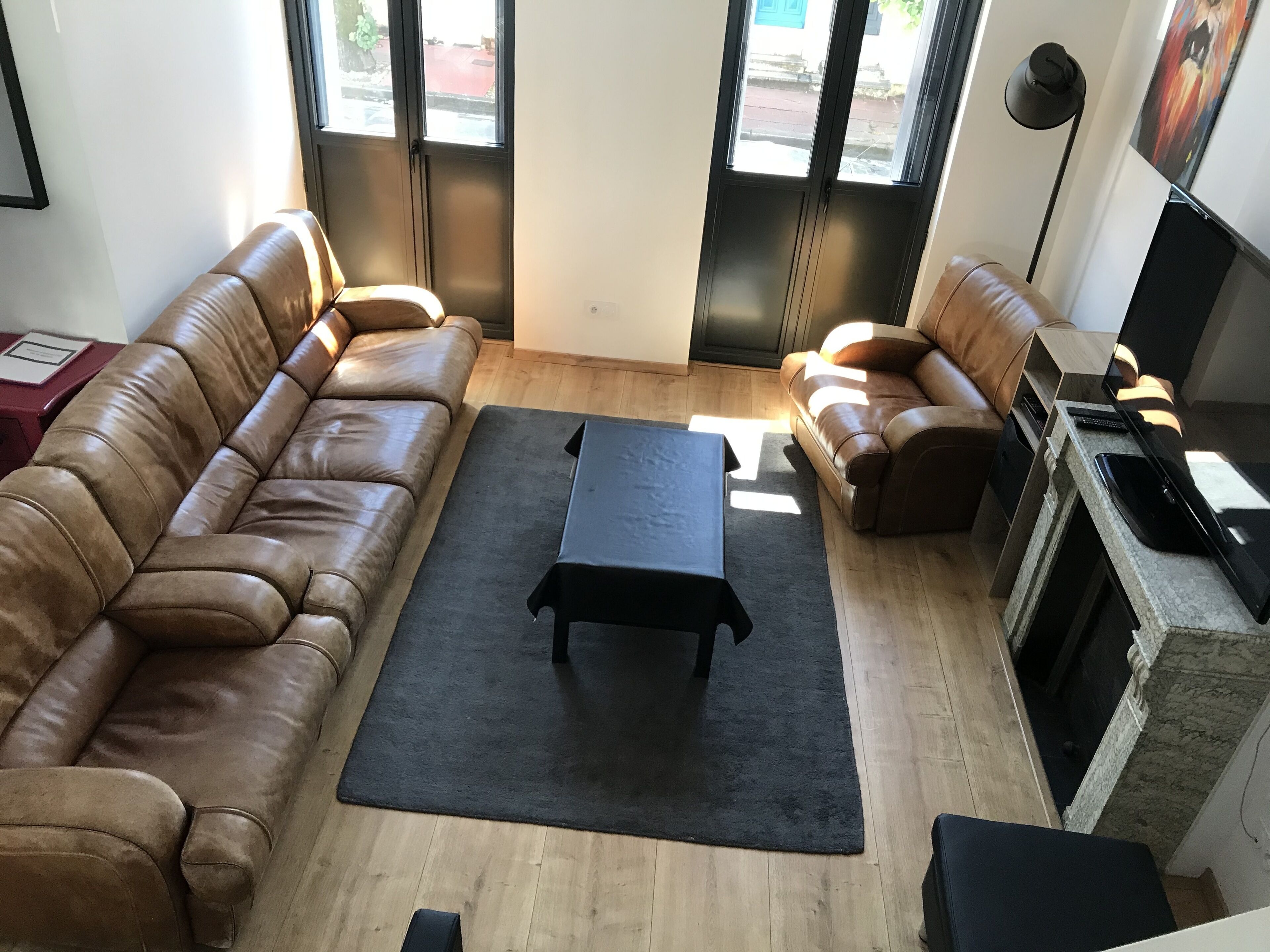 Una sala de estar con dos sofás de cuero marrón, una mesa de centro negra y una chimenea de piedra.