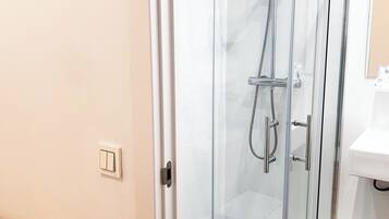 A modern bathroom with a glass-enclosed shower, a white toilet, and a wooden vanity.