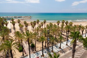 A beach with palm trees, a pier, and a clear blue sky.