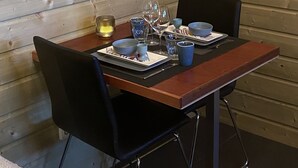 A wooden-paneled room with a table set for two, featuring a bull skull decoration, a framed picture, and a thermostat.