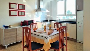 Cocina compacta con mesa, sillas y electrodomésticos básicos.