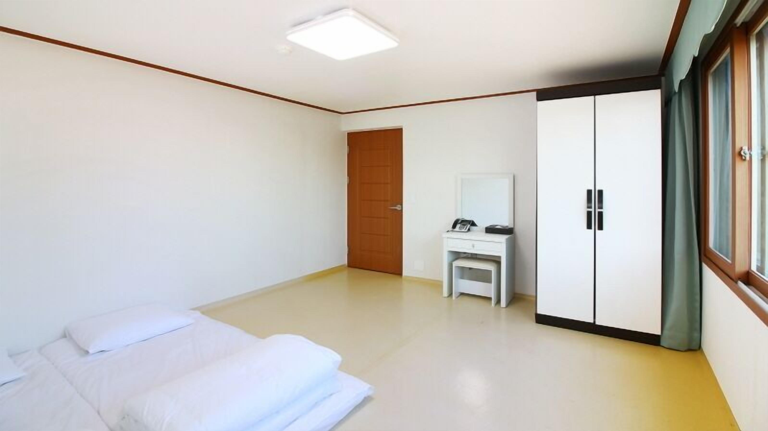 A bedroom with a bed, a desk, and a wardrobe.