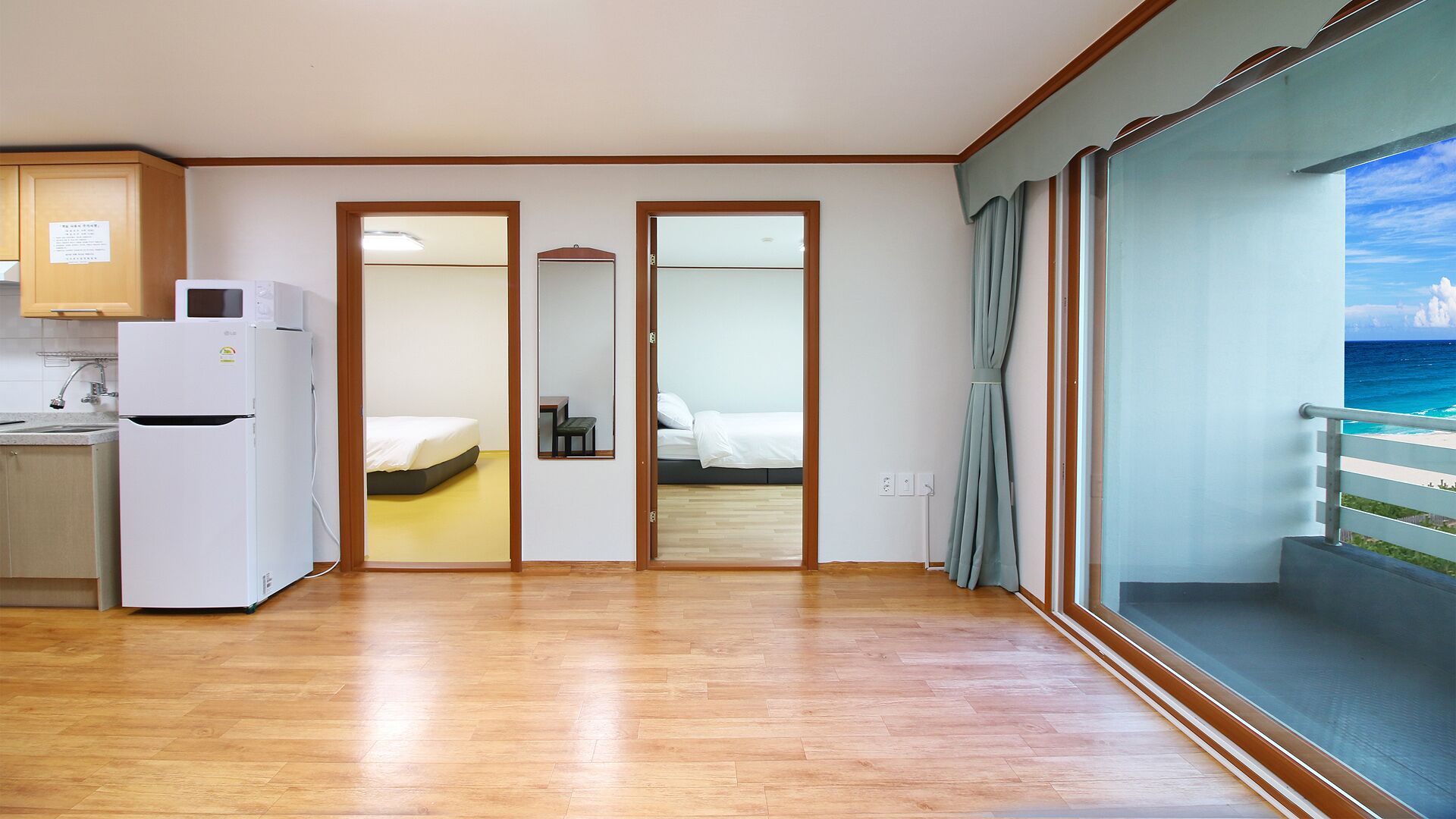 Habitación de hotel con kitchenette, cama, baño y balcón con vista al océano.