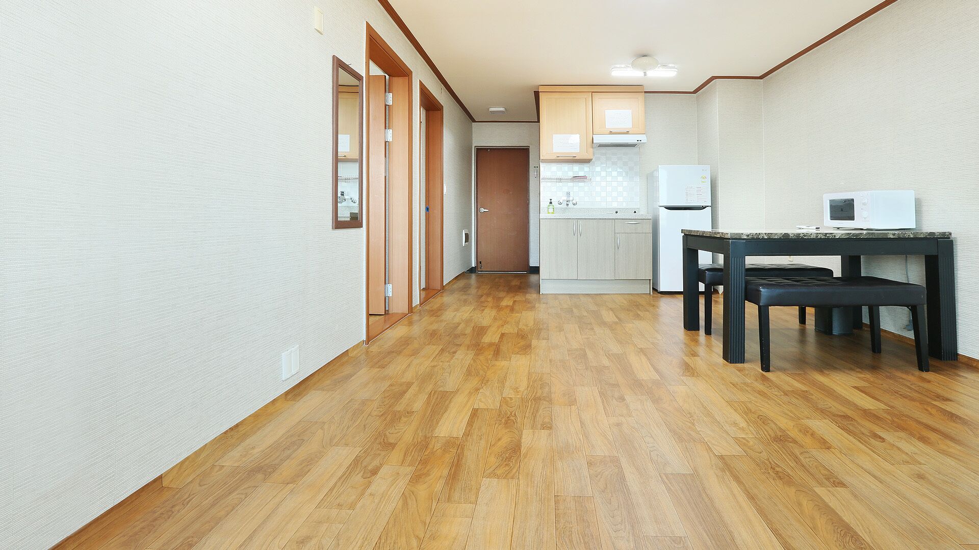 A hallway with wooden flooring leading to a kitchen area with a dining table and chairs.