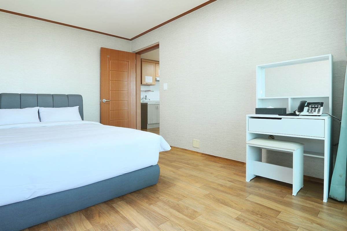 A hotel room with a bed, a desk, and a telephone.