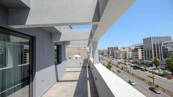 Un balcón con vista a la ciudad, arquitectura moderna y cielo despejado.