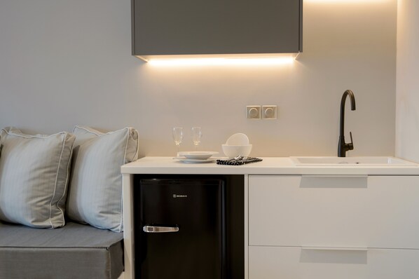 A compact kitchenette with a black dishwasher, white countertop, and a black faucet.