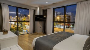 A hotel room with a large bed, a desk with a chair, a TV mounted on the wall, and large windows with curtains. - The Convo Syngrou Apartments (Kallithea)