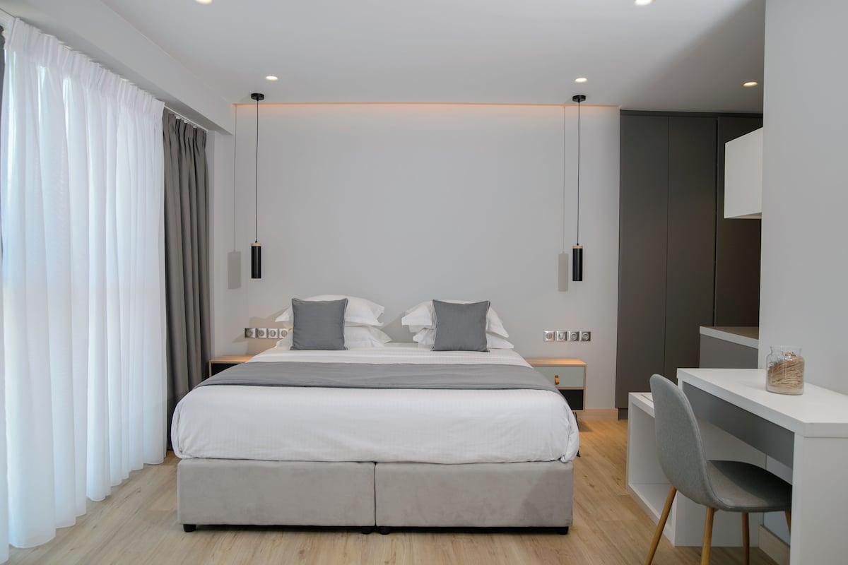 A modern bedroom with a large bed, bedside tables, a desk, and a chair.