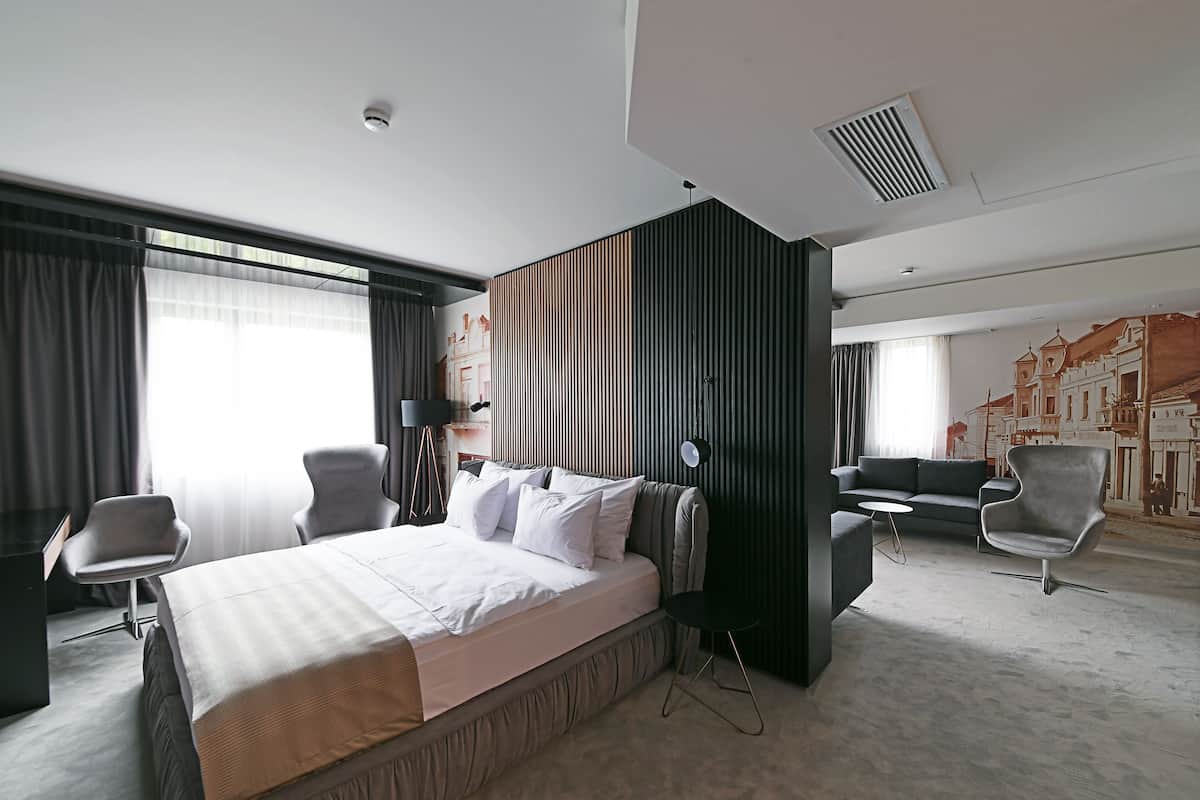 Una habitación de hotel moderna con una cama grande, dos sillones, un sofá y un escritorio.